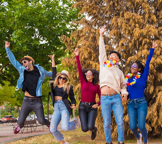 Group of multi ethnic friends partying in a park - Diverse young people jumping for joy at a summer party - Happy hour, lunch break and youth concept